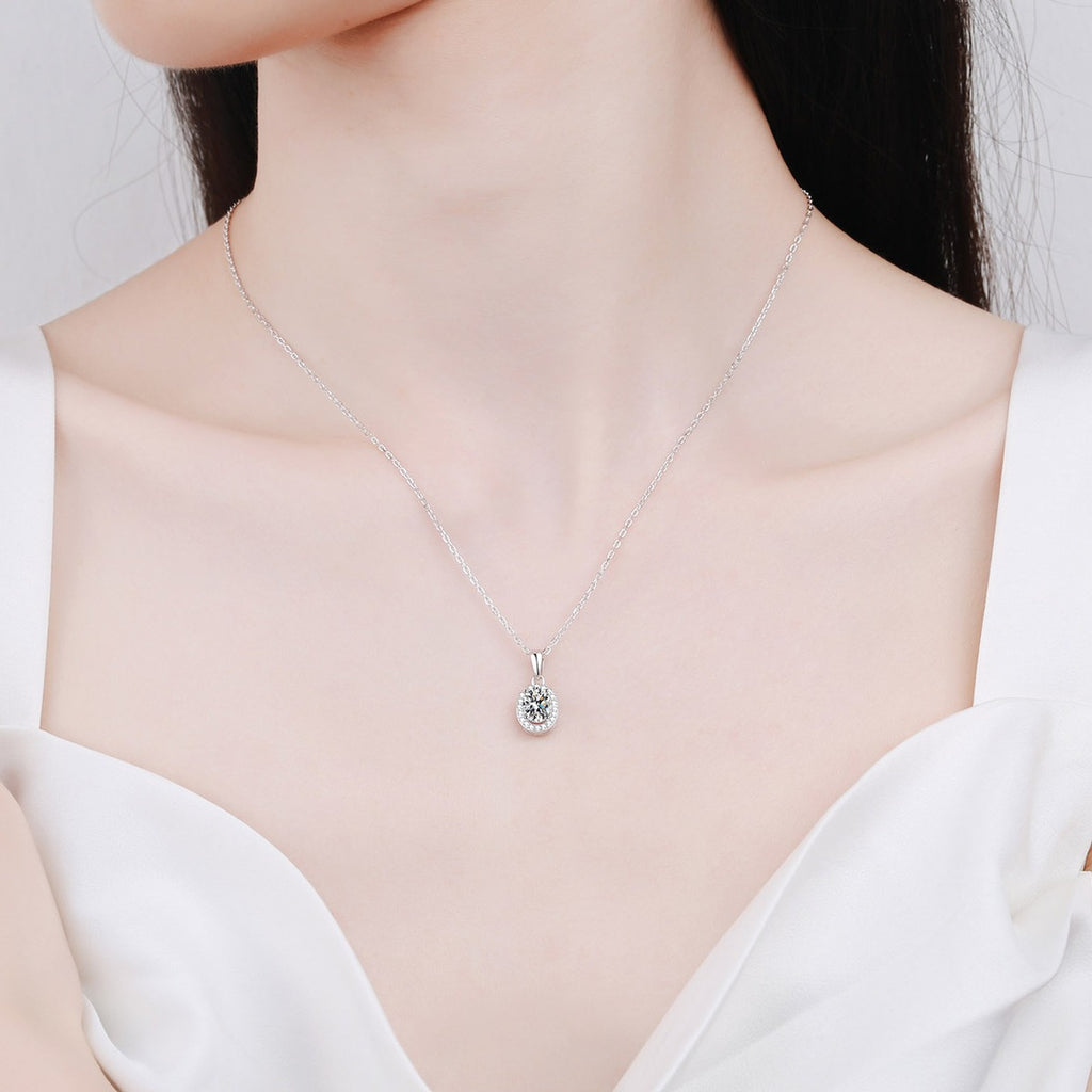 Oval Halo Moissanite Pendant Necklace with CZ in Rhodium-Plated S925 sterling silver worn on neckline by model showing scale and adjustable chain styling
