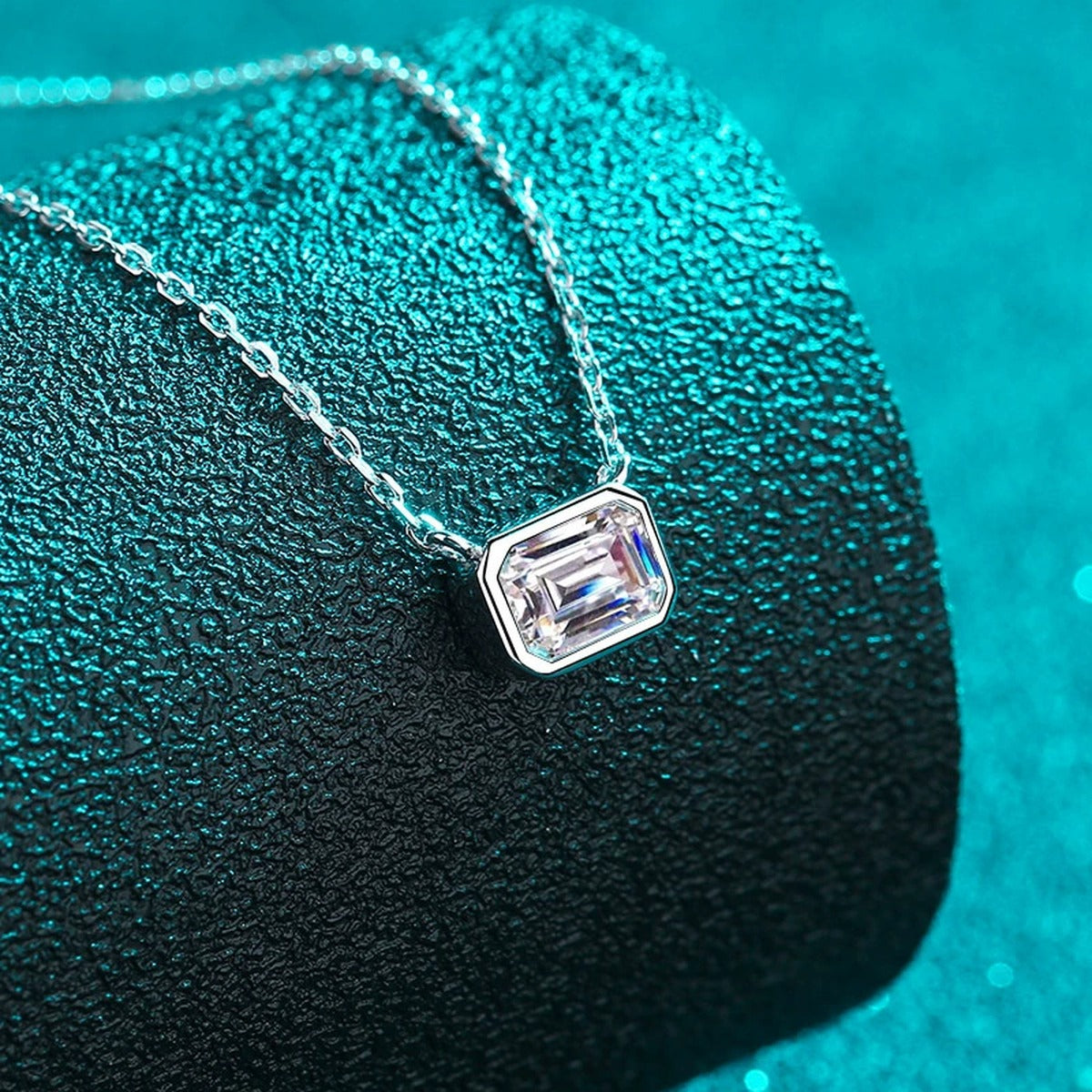 Emerald Cut Solitaire Moissanite Necklace in Rhodium-Plated S925 sterling silver blue display scene showing chain and stone layout