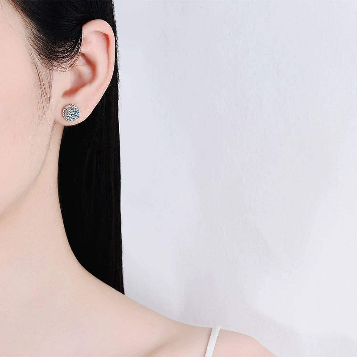 Halo Round Moissanite Stud Earrings in Rhodium-Plated S925 sterling silver worn on ear by model showing scale, placement, and stud earrings styling