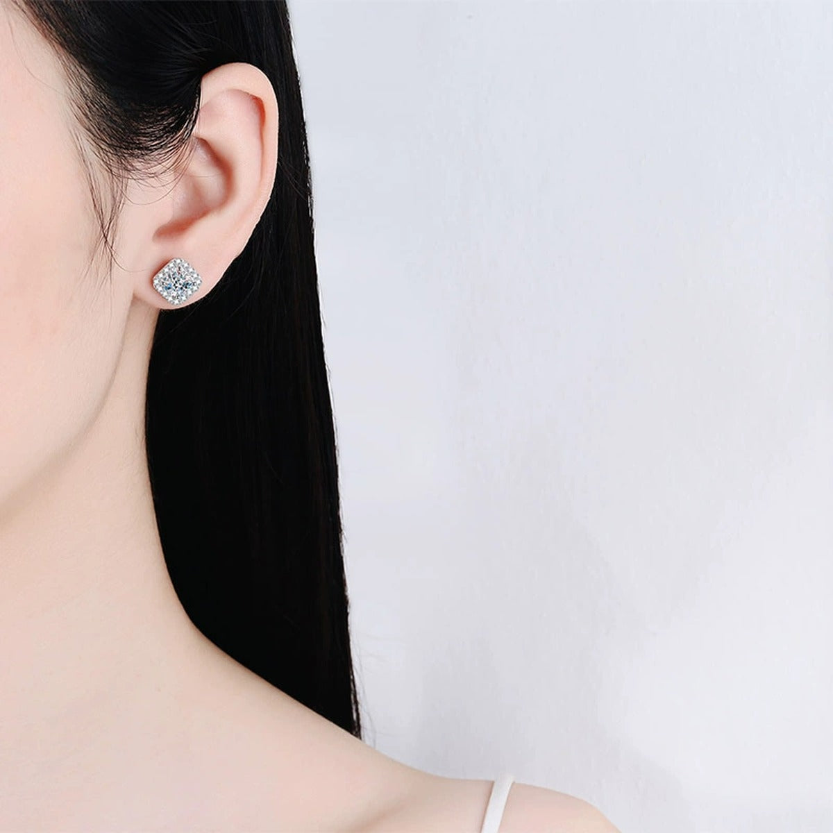 Princess Cut Halo Moissanite Stud Earrings with CZ in Rhodium-Plated S925 sterling silver worn on ear by model showing scale, placement, and stud earrings styling