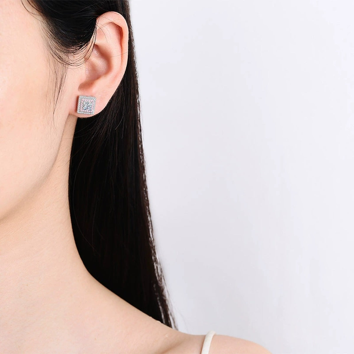 Princess Cut Moissanite Halo Stud Earrings with Pink CZ in Rhodium-Plated S925 sterling silver worn on ear by model showing scale, placement, and stud earrings styling