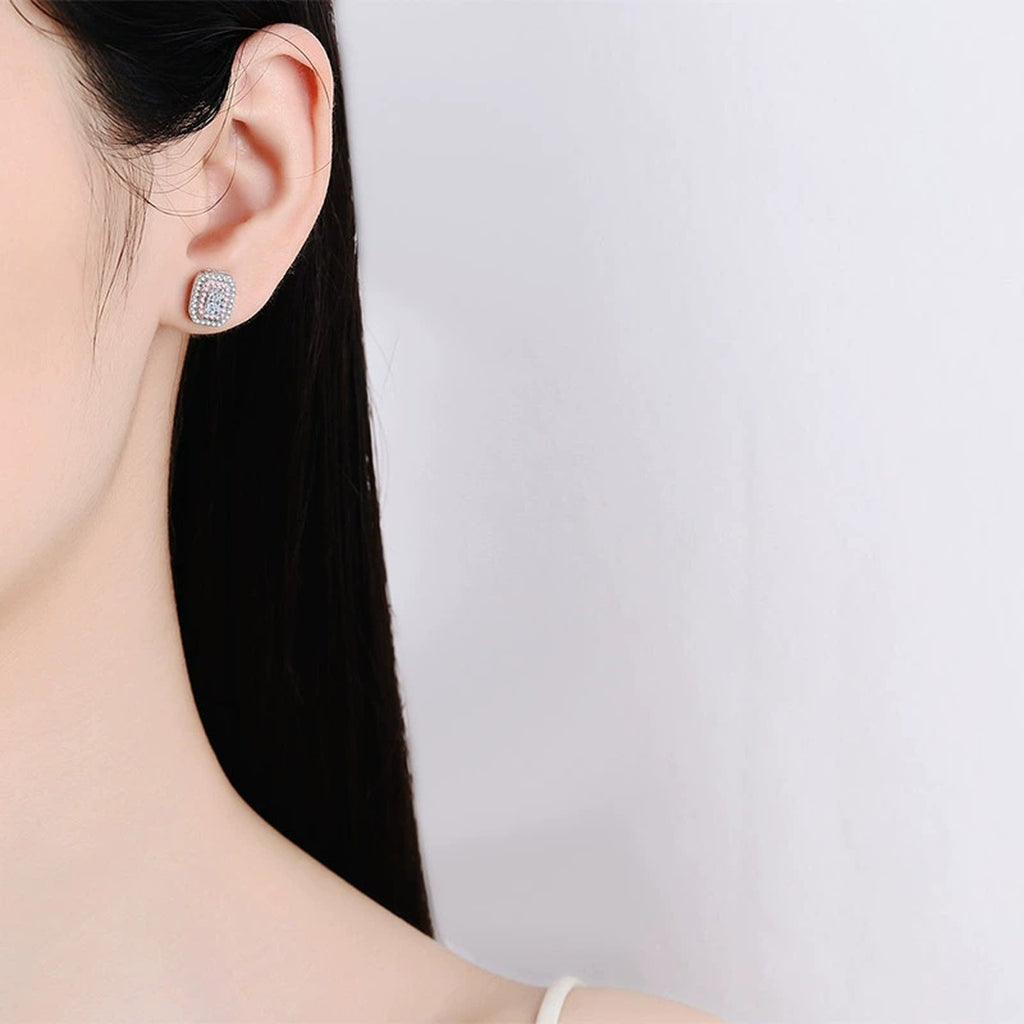 Emerald and Radiant Cut Moissanite Halo Stud Earrings with Pink CZ in Rhodium-Plated S925 sterling silver worn on ear by model showing scale, placement, and stud earrings styling