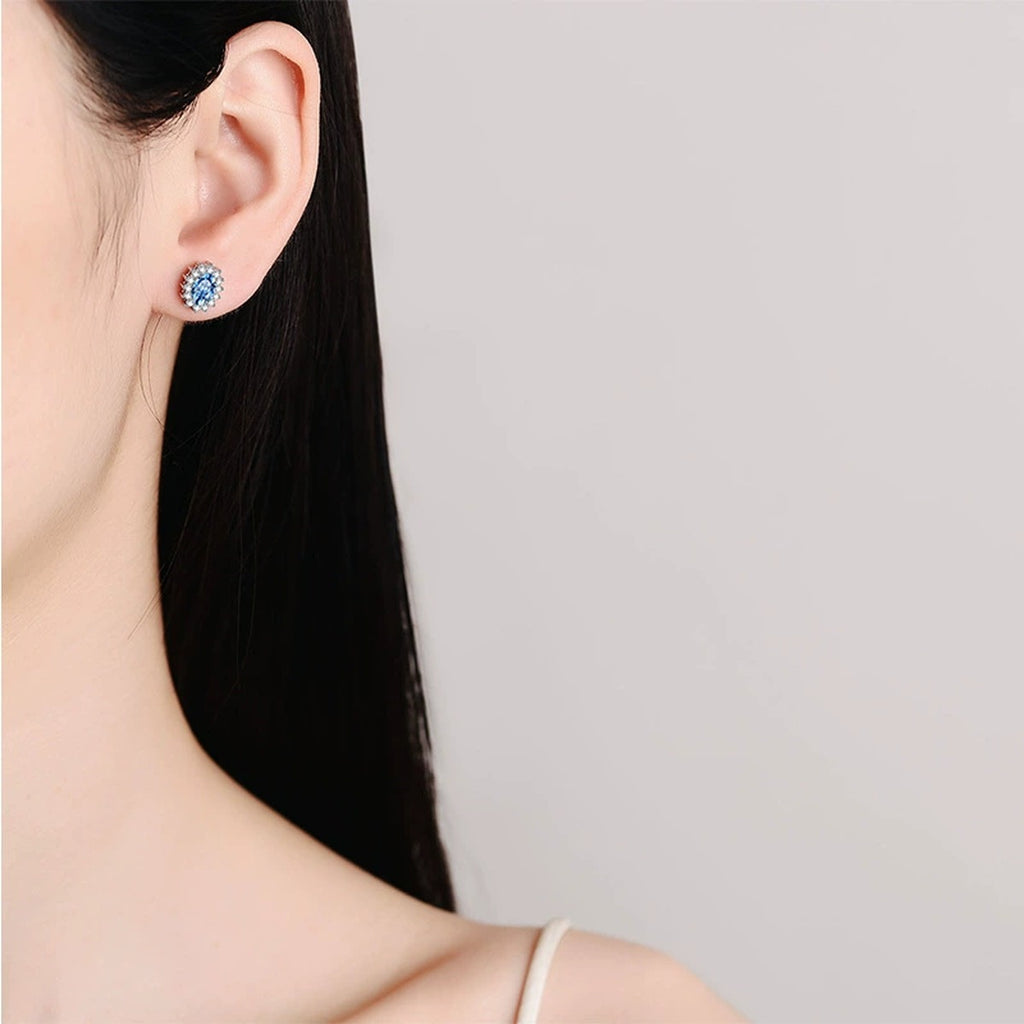Blue Oval Moissanite Halo Stud Earrings with CZ in Rhodium-Plated S925 sterling silver worn on ear by model showing scale, placement, and stud earrings styling