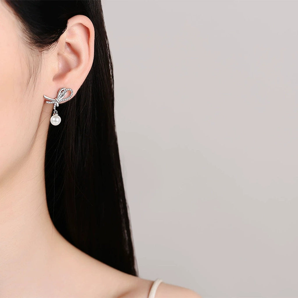 Bow Pearl Moissanite Stud Dangle Earrings in Rhodium-Plated S925 sterling silver worn on ear by model showing scale, placement, and stud dangle earrings styling