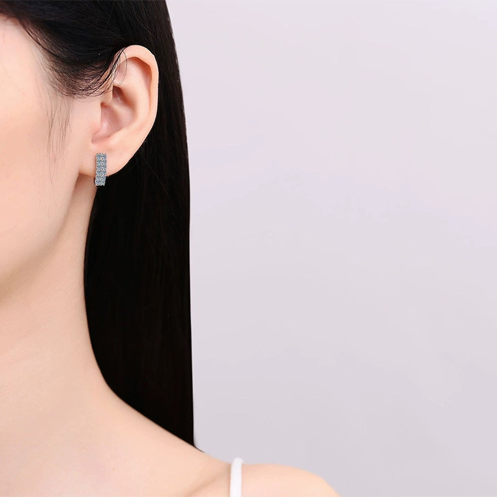 Pave Moissanite Huggie Hoop Earrings in Rhodium-Plated S925 sterling silver worn on ear by model showing scale, placement, and huggie hoop earrings styling