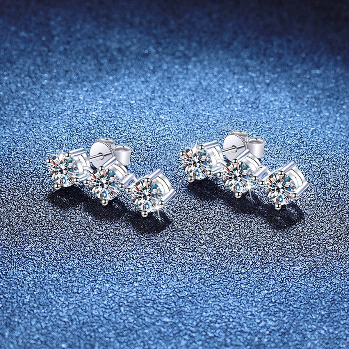 Three-Stone Moissanite Stud Earrings in White Gold-Plated S925 Sterling Silver blue scene close-up view