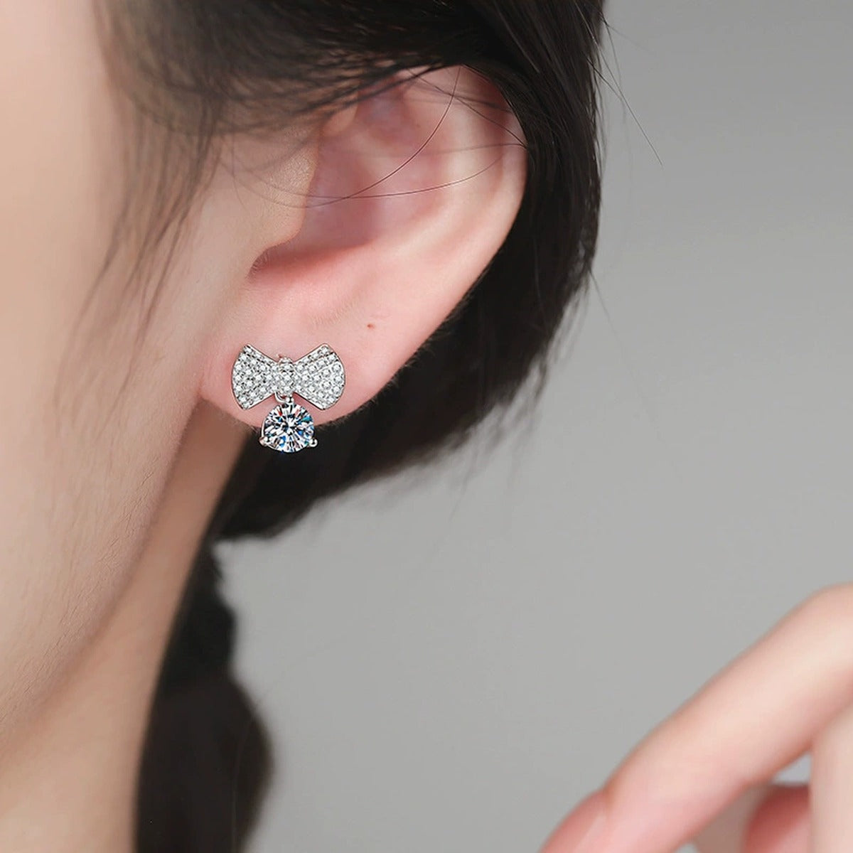 Bow Drop Moissanite Stud Earrings in White Gold-Plated S925 Sterling Silver with CZ worn on ear by model
