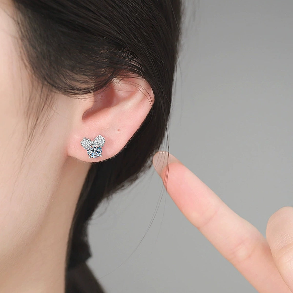 Bow Moissanite Stud Earrings in White Gold-Plated S925 Sterling Silver with CZ worn on ear by model