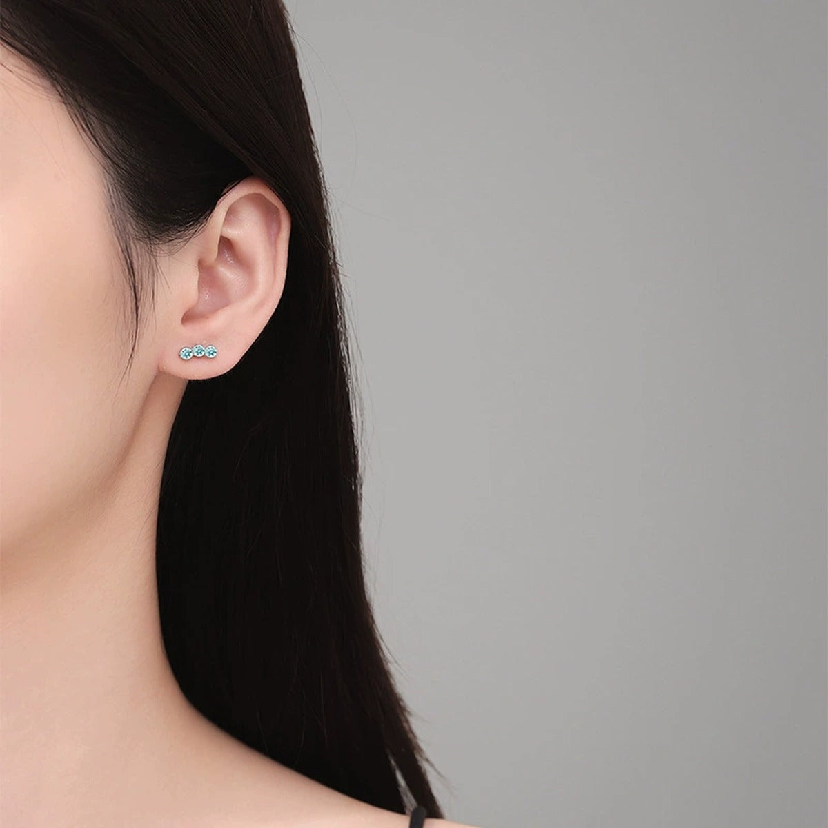 Green Moissanite Three-Stone Stud Earrings in White Gold-Plated S925 Sterling Silver worn on ear by model