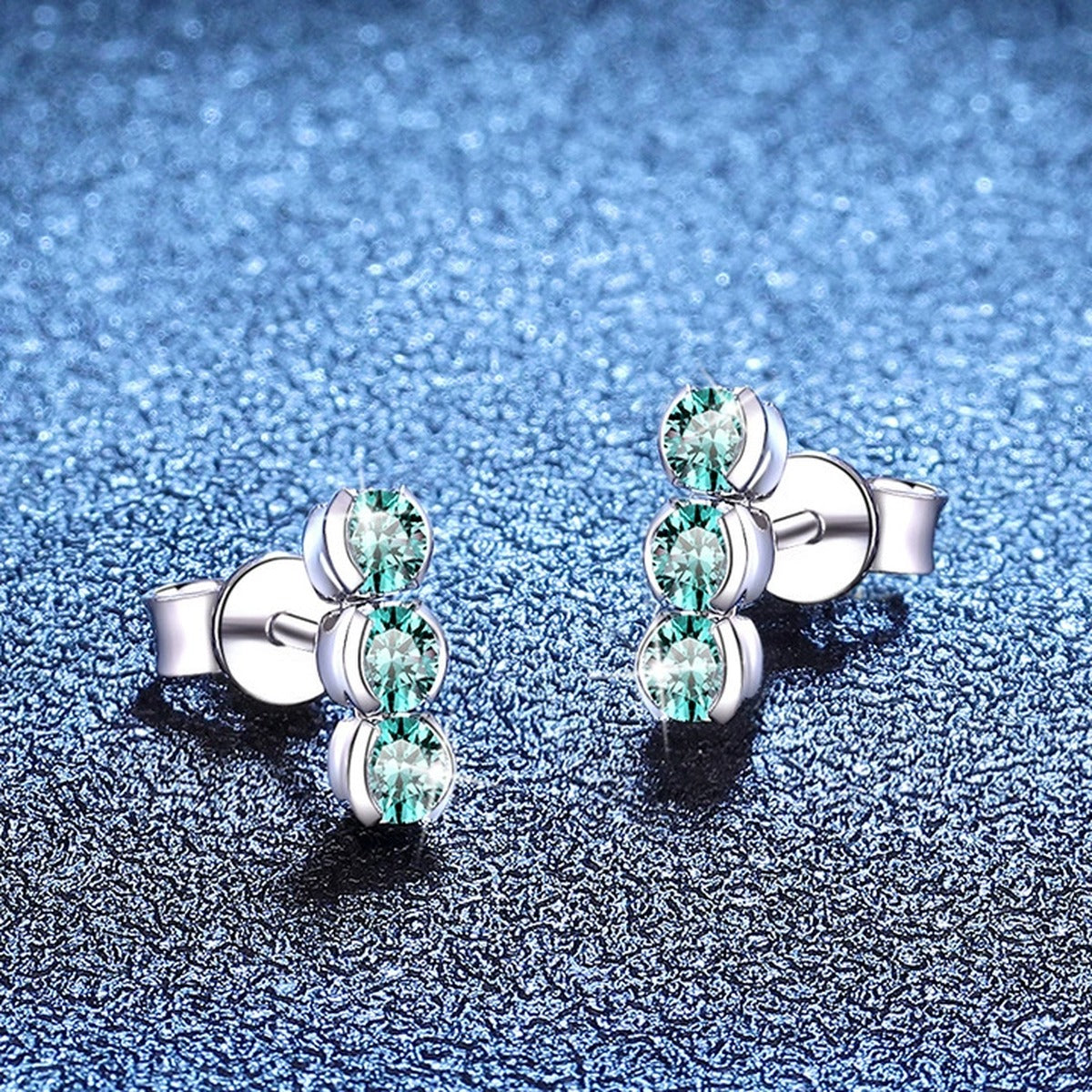 Green Moissanite Three-Stone Stud Earrings in White Gold-Plated S925 Sterling Silver blue scene angled view