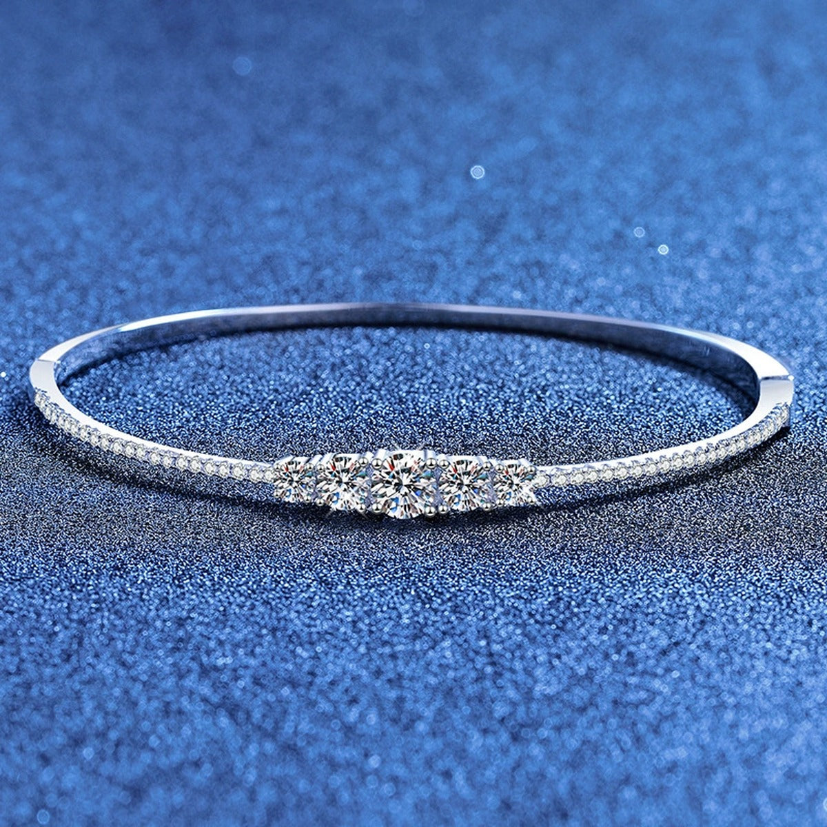 Graduated Moissanite Bangle Bracelet with CZ styled on blue display background showing moissanite sparkle and chain detail