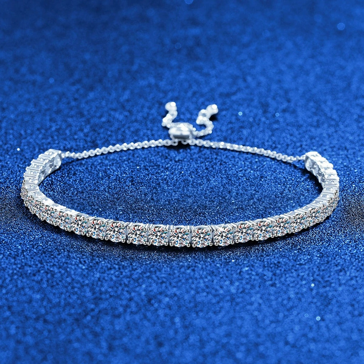 Round Moissanite Tennis Bracelet styled on blue display background showing moissanite sparkle and chain detail