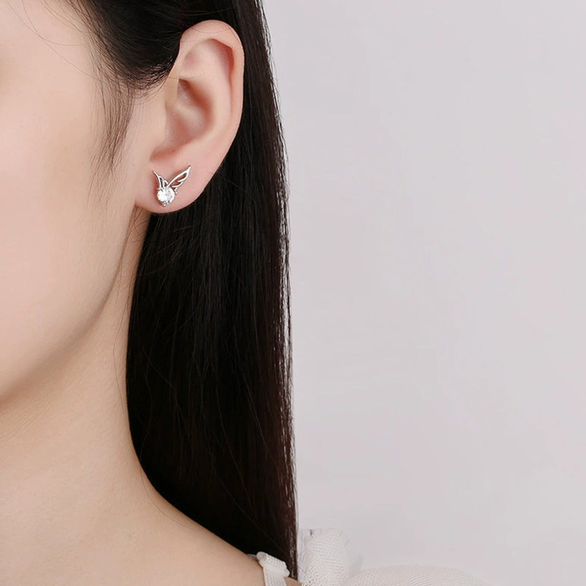 Angel Wing Round Moissanite Stud Earrings in Gold-Plated S925 sterling silver worn on ear by model showing scale, placement, and stud earrings styling