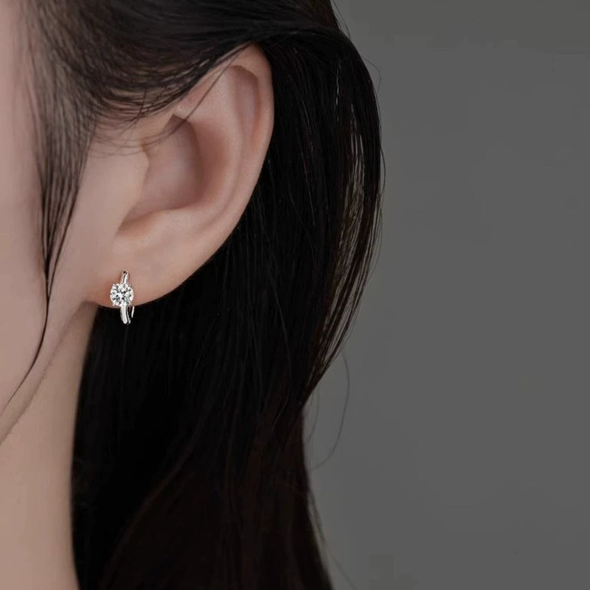Four-Prong Round Moissanite Huggie Hoop Earrings in Gold-Plated S925 sterling silver worn on ear by model showing scale, placement, and huggie hoop earrings styling