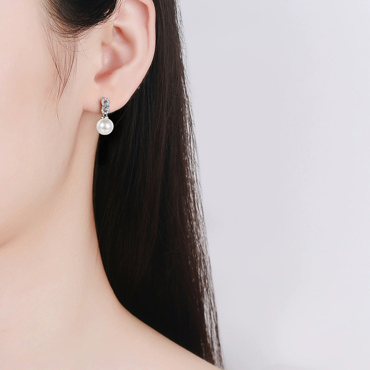 Infinity Round Moissanite and Pearl Stud Dangle Earrings with CZ in White Gold-Plated S925 sterling silver worn on ear by model showing scale, placement, and stud dangle earrings styling