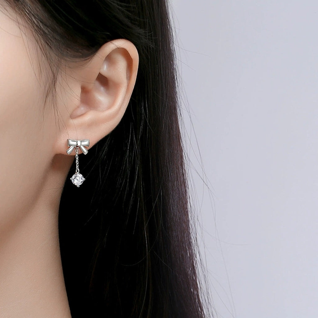 Bowknot Round Moissanite Stud Dangle Earrings in White Gold-Plated S925 sterling silver worn on ear by model showing scale, placement, and stud dangle earrings styling