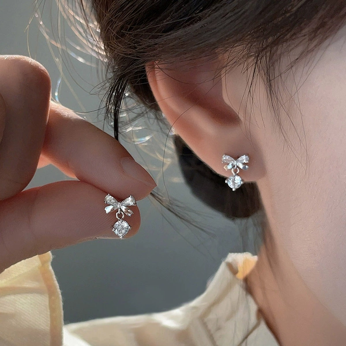 Bowknot Round Moissanite Stud Dangle Earrings with CZ in White Gold-Plated S925 sterling silver worn on ear by model showing scale, placement, and stud dangle earrings styling