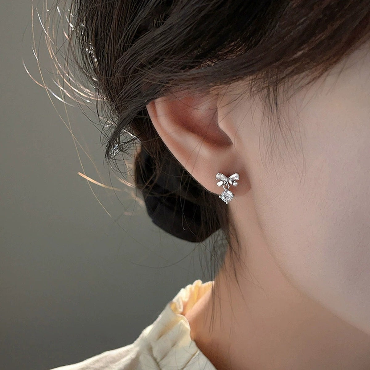 Bowknot Round Moissanite Stud Dangle Earrings with CZ in White Gold-Plated S925 sterling silver worn on ear by model showing scale, placement, and stud dangle earrings styling