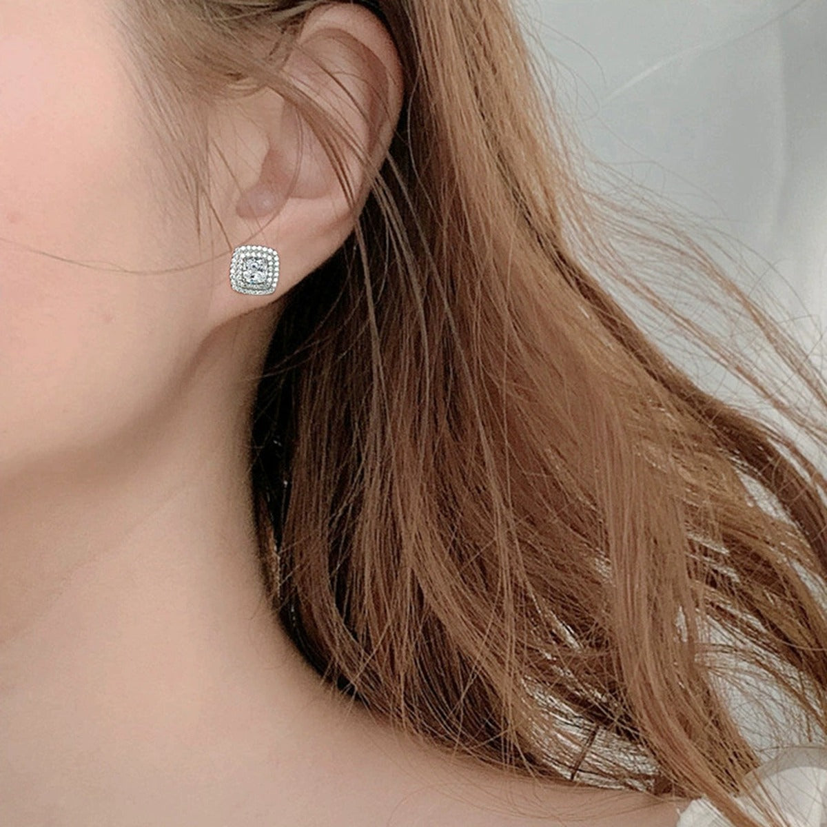 Cushion Halo Round Moissanite Stud Earrings with CZ in White Gold-Plated S925 sterling silver worn on ear by model showing scale, placement, and stud earrings styling