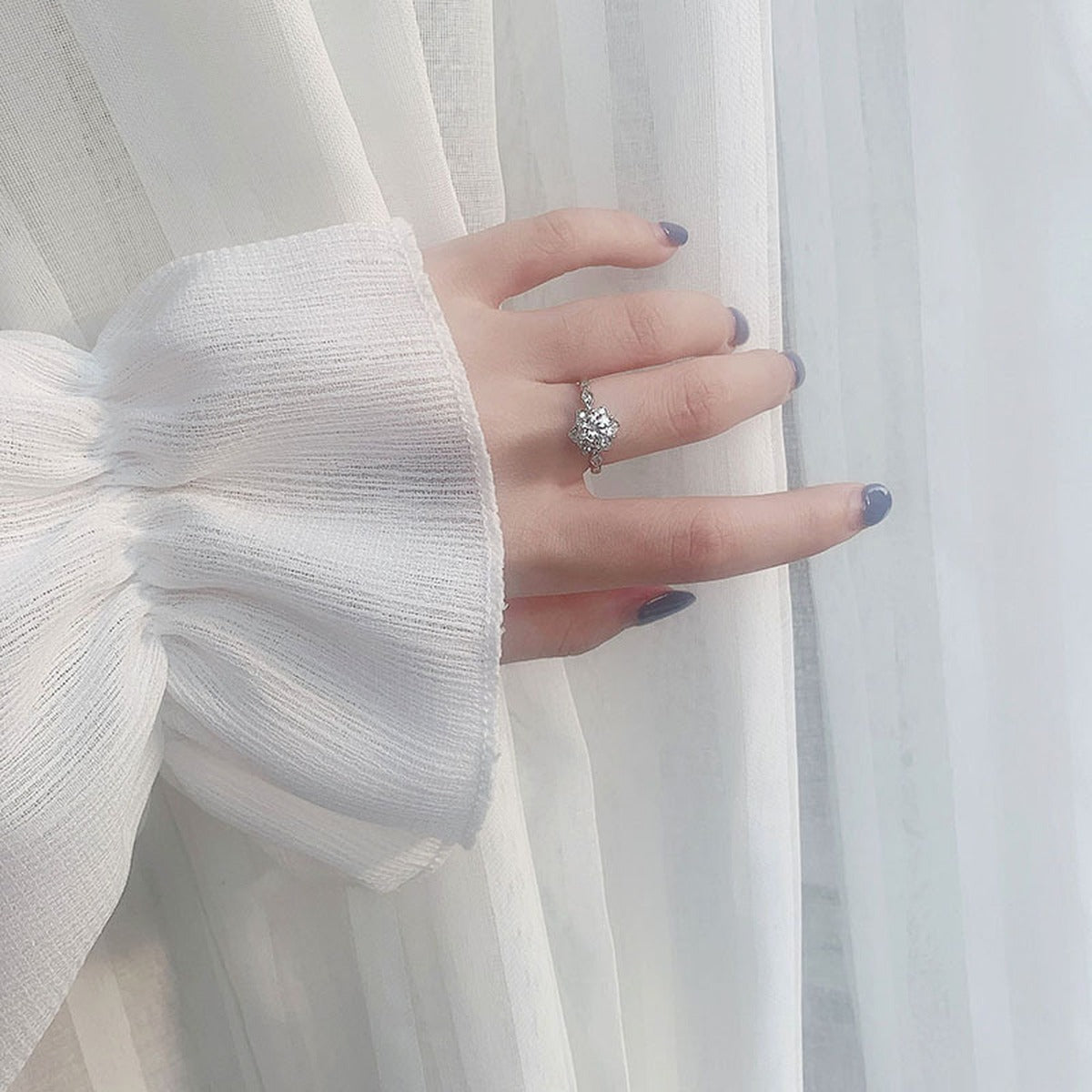 Floral Round Moissanite Adjustable Engagement Ring with CZ worn on hand to show scale, band width, and ring profile