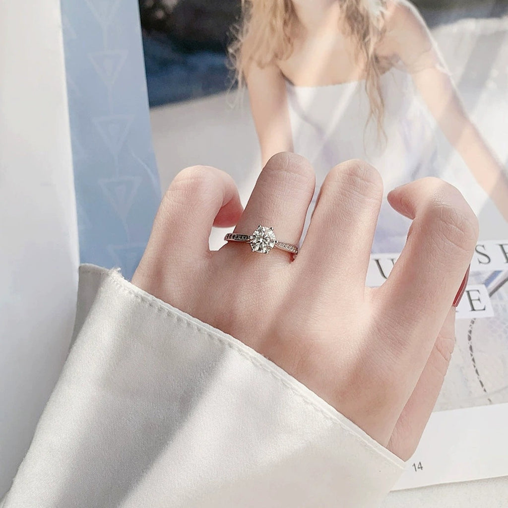 Six-Prong Round Moissanite Engagement Ring with CZ worn on hand to show scale, band width, and ring profile