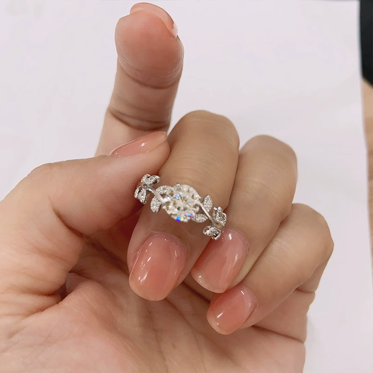 Leaf Vine Four-Prong Round Moissanite Engagement Ring with CZ worn on hand to show scale, band width, and ring profile