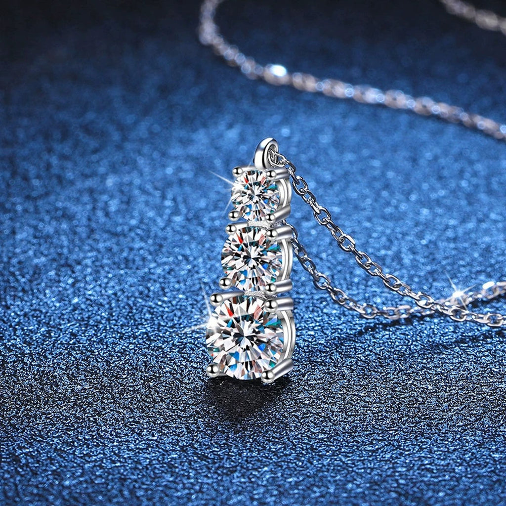 Graduated Three-Stone Moissanite Drop Necklace in Platinum-Plated S925 Sterling Silver blue background angled detail view
