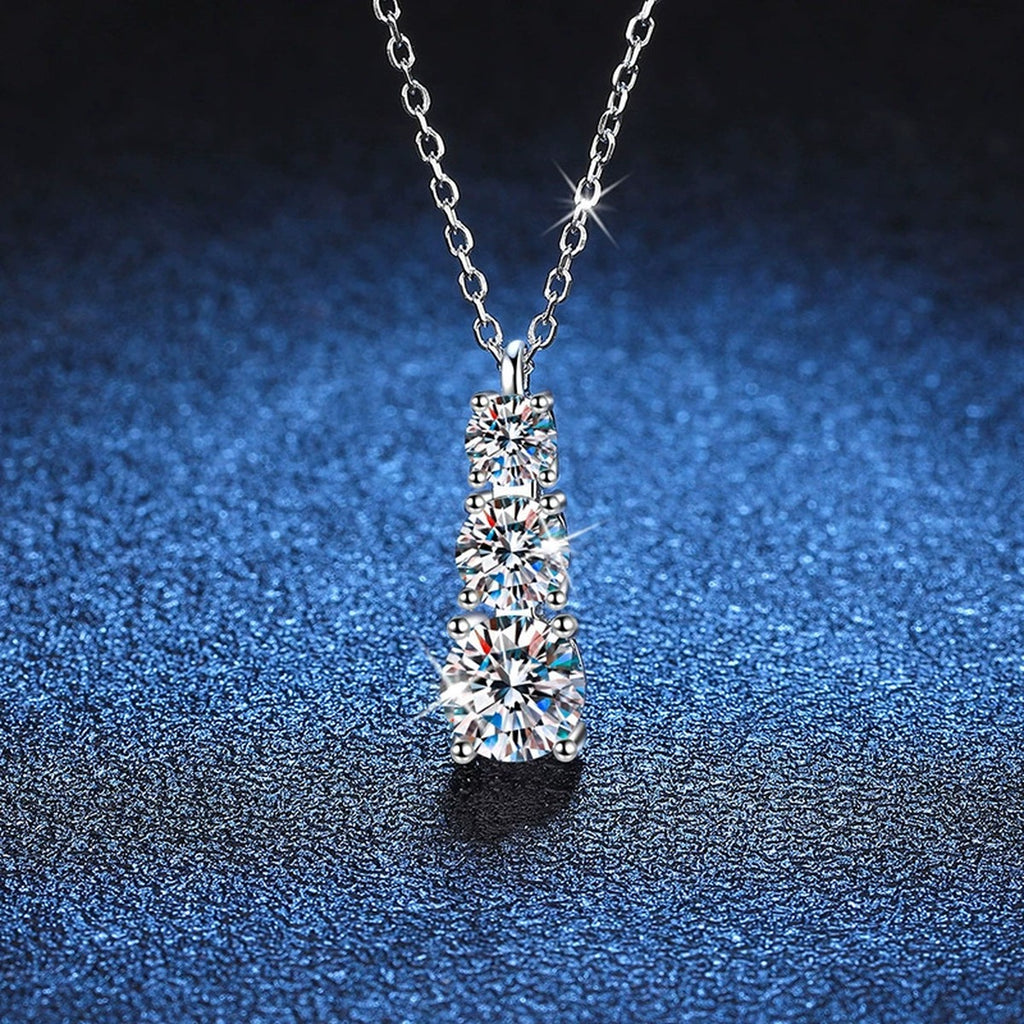 Graduated Three-Stone Moissanite Drop Necklace in Platinum-Plated S925 Sterling Silver blue background close-up view