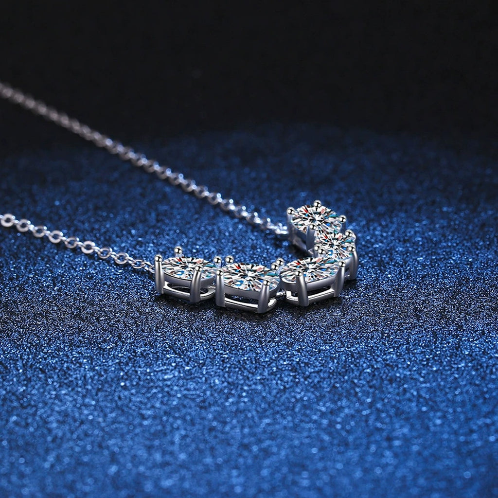Graduated Five-Stone Moissanite Necklace in Platinum-Plated S925 Sterling Silver blue background angled detail view