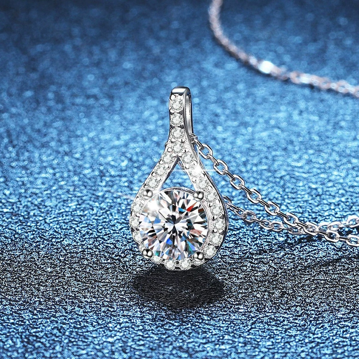 Pear Halo Moissanite Pendant Necklace in Platinum-Plated S925 Sterling Silver blue background angled detail view