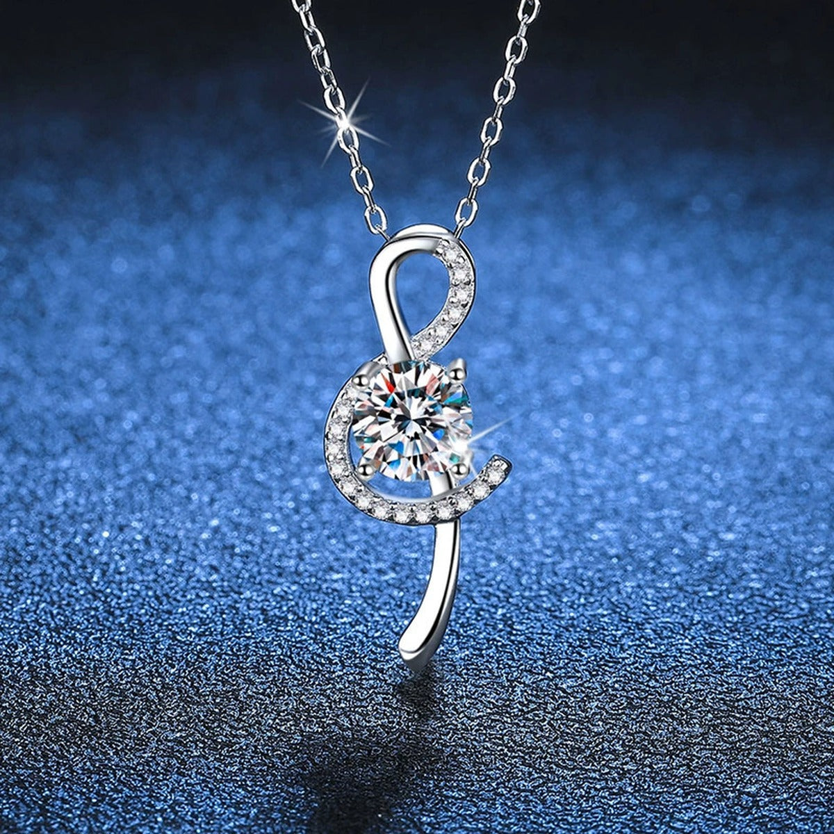Crescent Moissanite Pendant Necklace in Platinum-Plated S925 Sterling Silver blue background close-up view