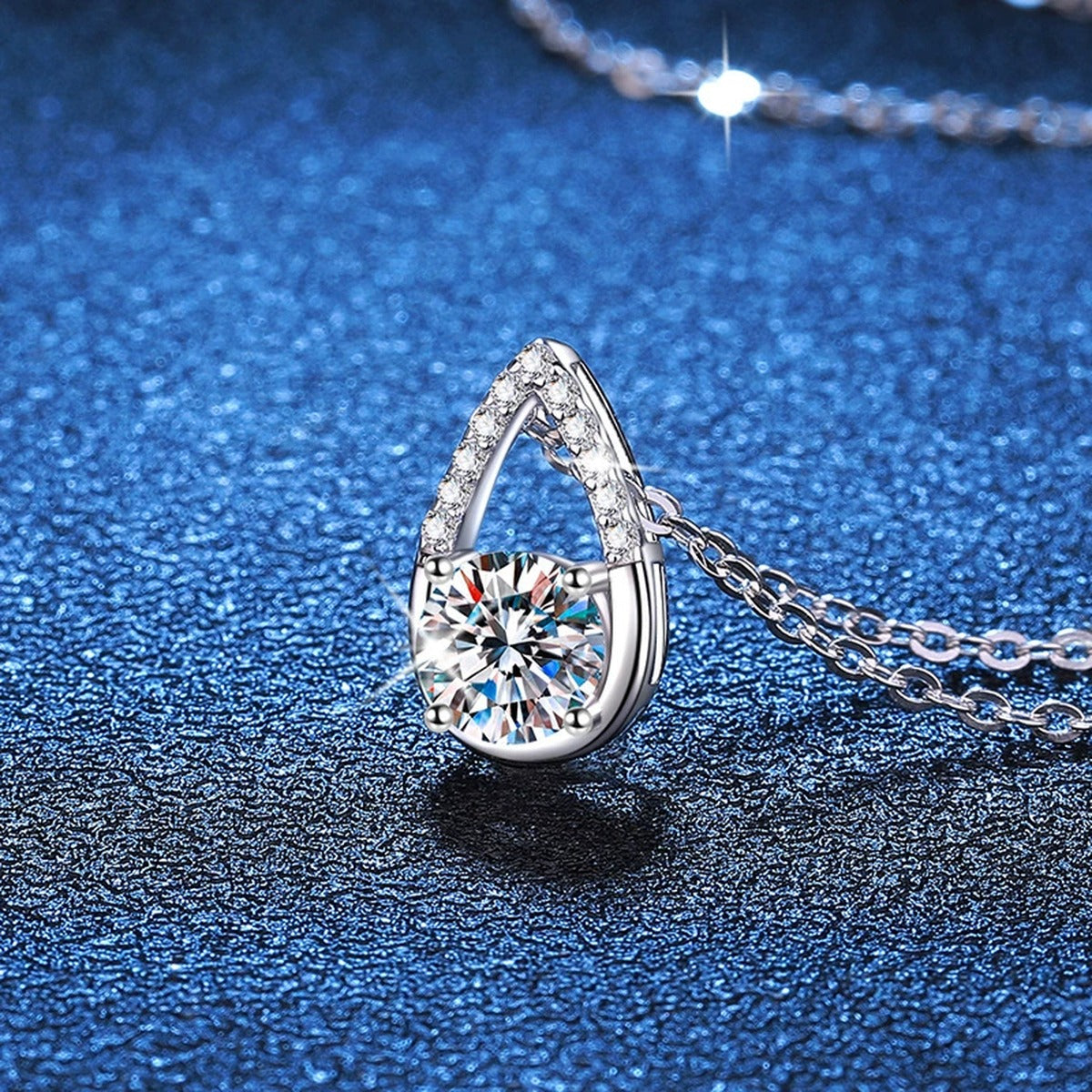 Teardrop Moissanite Pendant Necklace in Platinum-Plated S925 Sterling Silver blue background close-up view