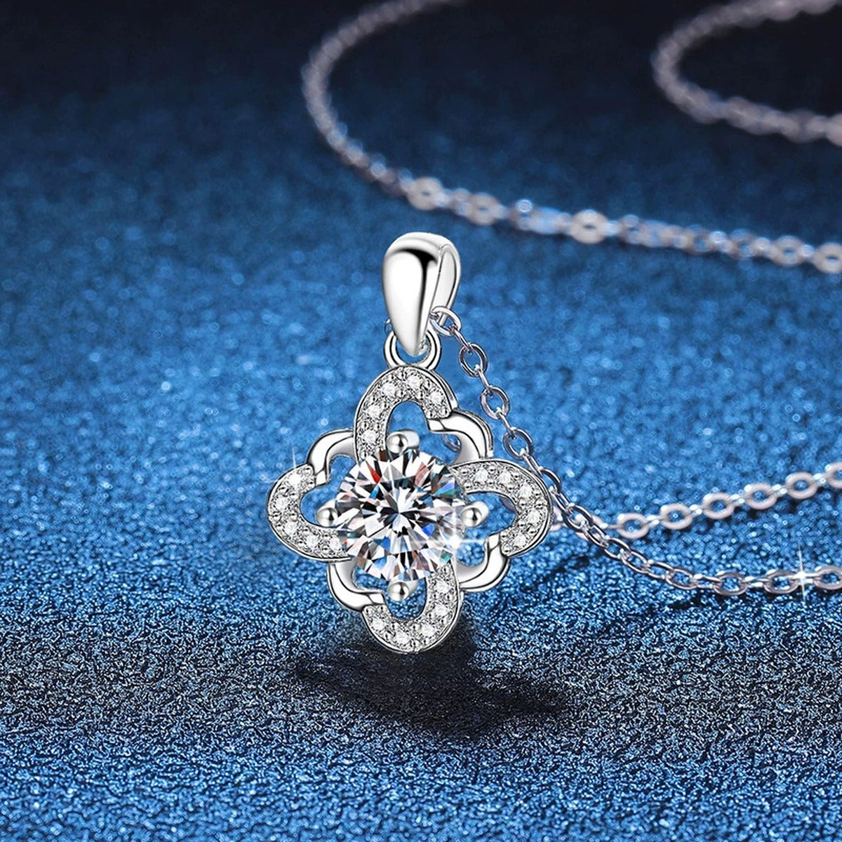 Quatrefoil Halo Moissanite Pendant Necklace in Platinum-Plated S925 Sterling Silver blue background angled view