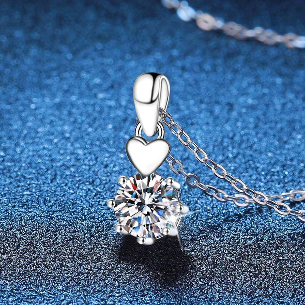 Heart Charm Moissanite Pendant Necklace in Platinum-Plated S925 Sterling Silver blue background angled view