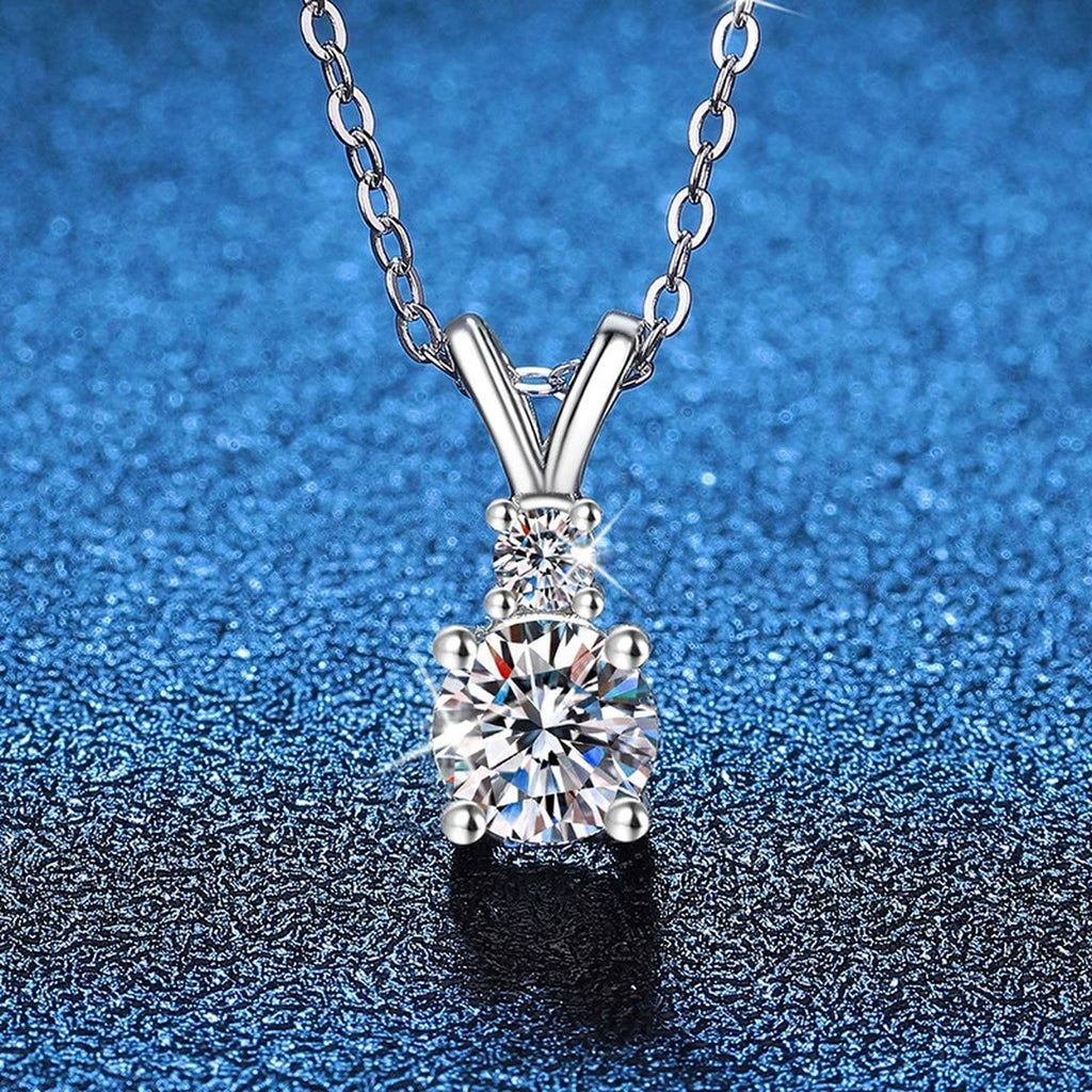 Graduated Drop Moissanite Pendant Necklace in Platinum-Plated S925 Sterling Silver blue background close-up view