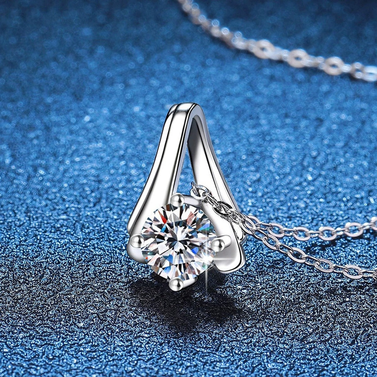 Teardrop Solitaire Moissanite Pendant Necklace in Platinum-Plated S925 Sterling Silver blue background close-up view