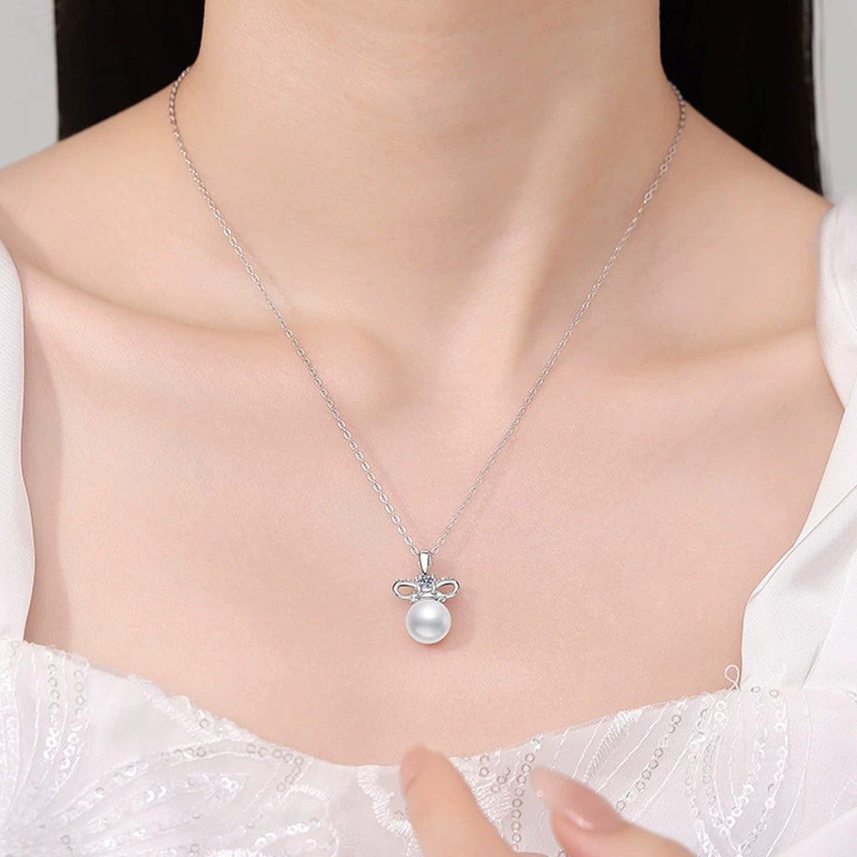 Bow Moissanite Freshwater Pearl Pendant Necklace with Cubic Zirconia in White Gold-Plated S925 Sterling Silver worn on neckline by model
