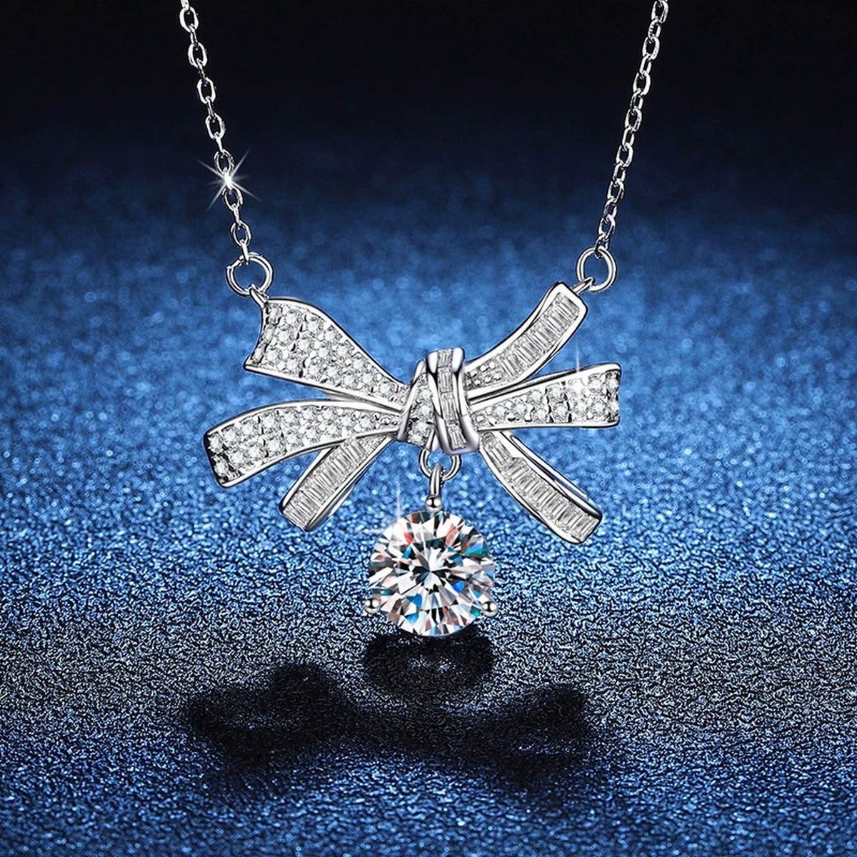 Bow Drop Moissanite Pendant Necklace in Platinum-Plated S925 Sterling Silver blue background angled view