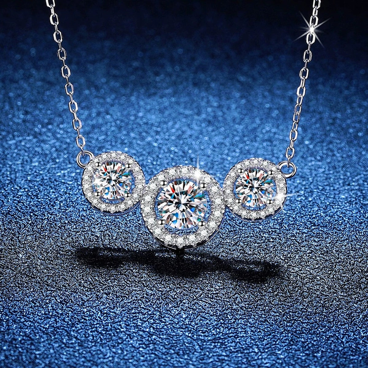 Three-Stone Halo Moissanite Station Necklace in Platinum-Plated S925 Sterling Silver blue background angled view