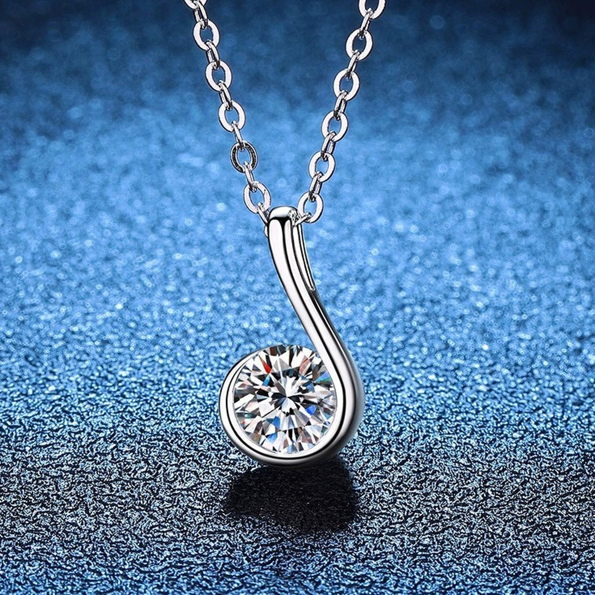Curved Loop Moissanite Pendant Necklace in S925 Sterling Silver blue background angled view