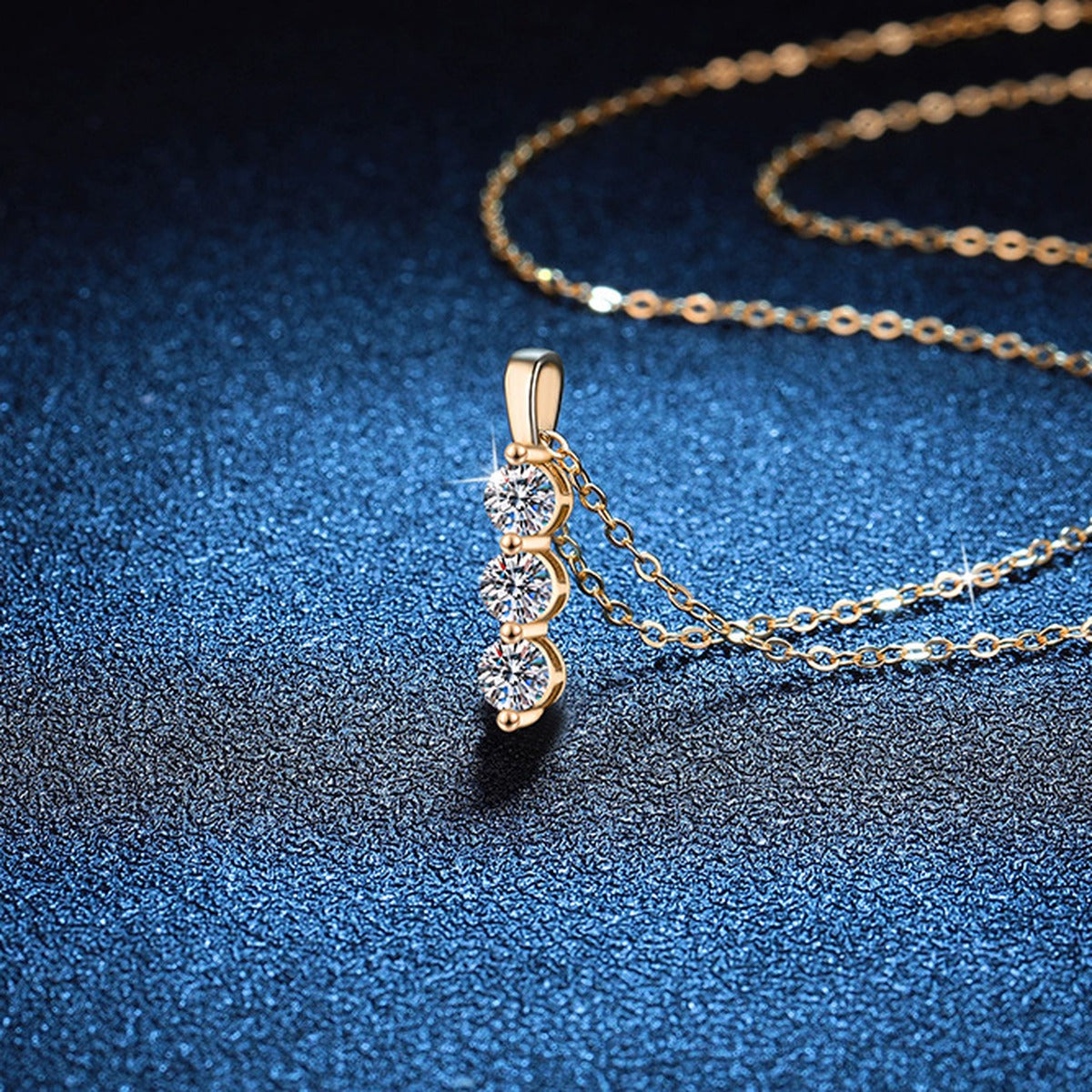 Vertical Three-Stone Moissanite Drop Necklace in S925 Sterling Silver blue background close-up view