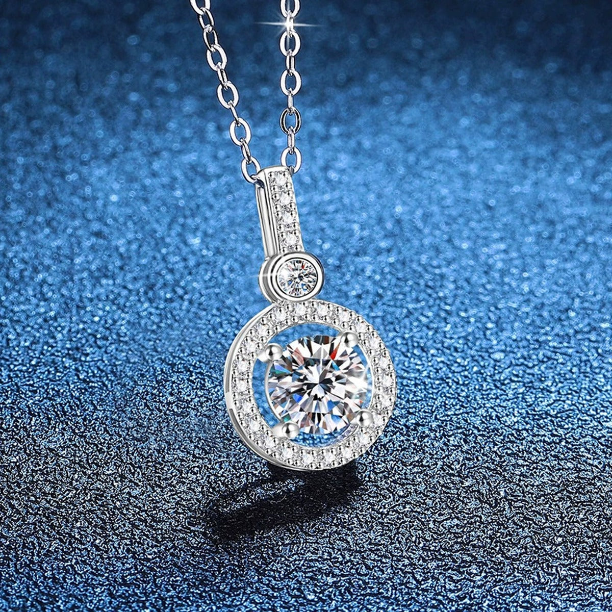 Round Halo Drop Moissanite Pendant Necklace in Platinum-Plated S925 Sterling Silver blue background close-up view