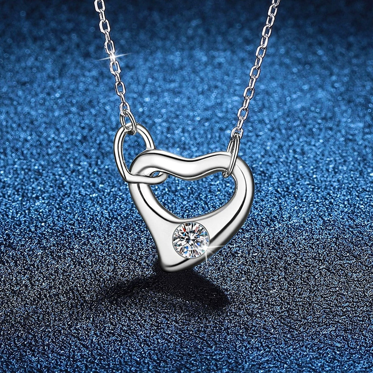 Open Heart Knot Moissanite Pendant Necklace in Platinum-Plated S925 Sterling Silver blue background angled view