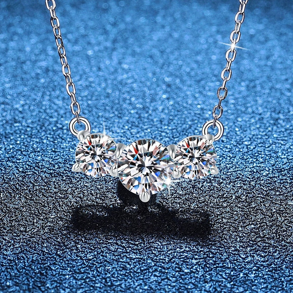 Three-Stone Moissanite Station Necklace in Platinum-Plated S925 Sterling Silver blue background close-up view