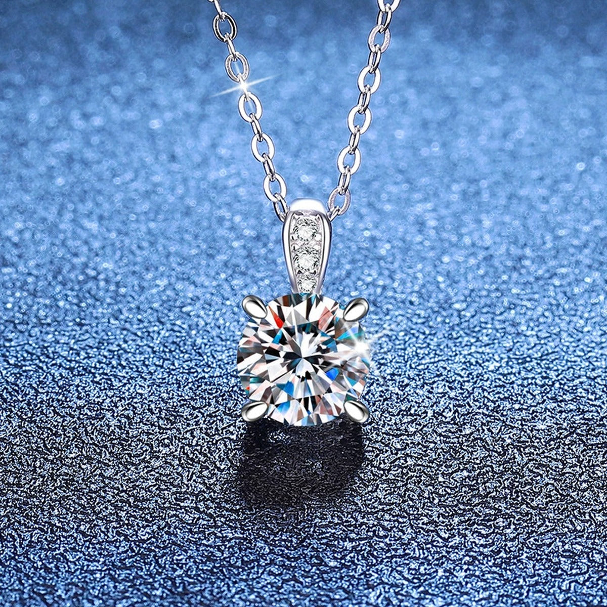 Round Moissanite Pendant Necklace with Cubic Zirconia Bail in S925 Sterling Silver blue background angled view