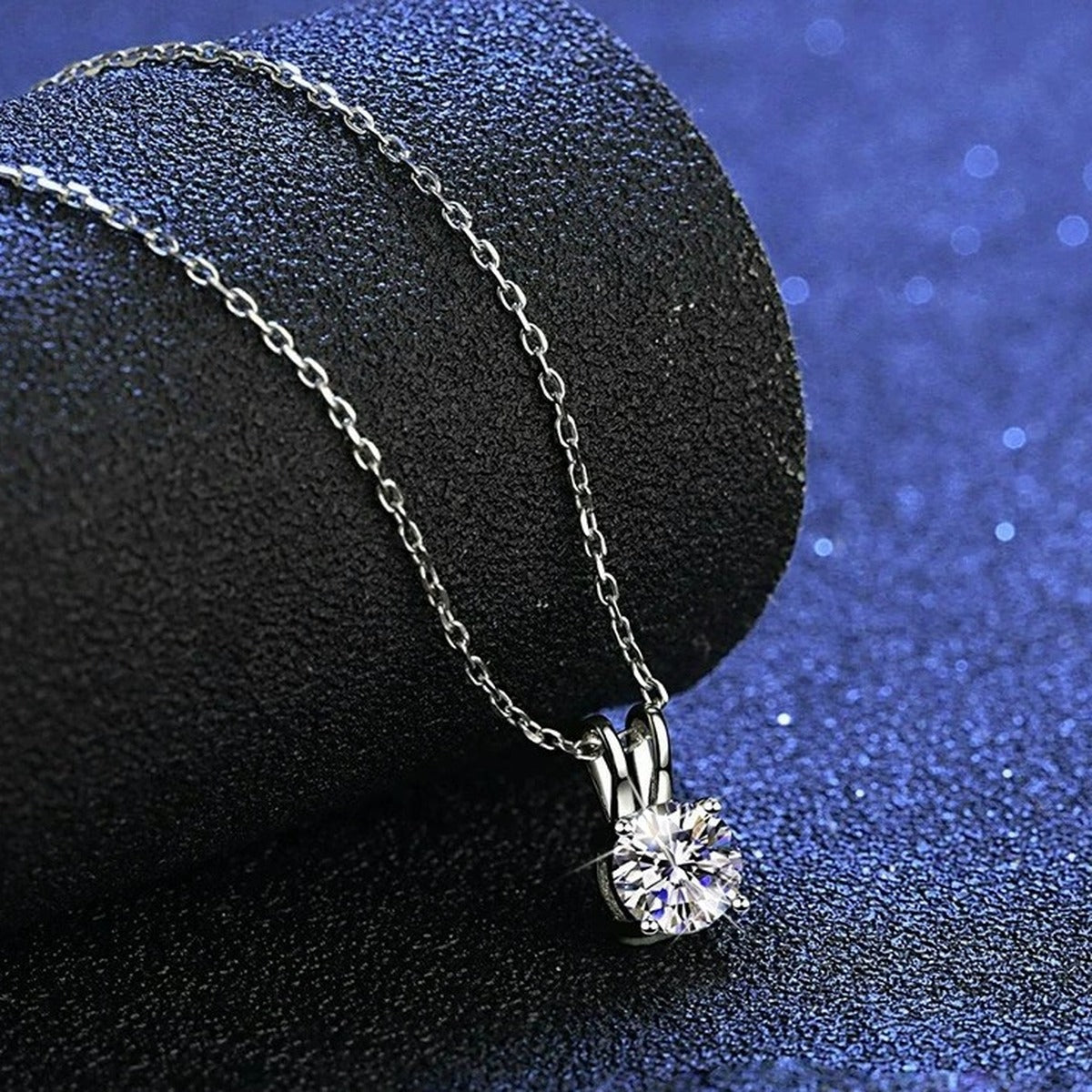 Round Solitaire Moissanite Pendant Necklace in Platinum-Plated S925 Sterling Silver blue background angled view