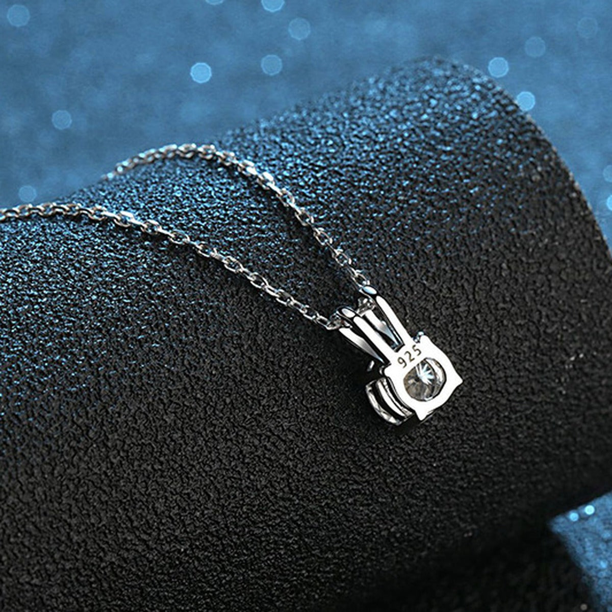Round Solitaire Moissanite Pendant Necklace in Platinum-Plated S925 Sterling Silver blue background close-up view