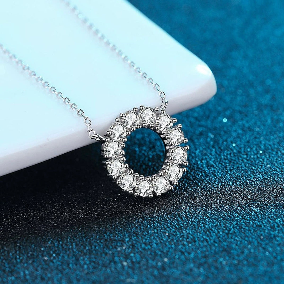 Circle Moissanite Pendant Necklace in Platinum-Plated S925 Sterling Silver blue background angled view
