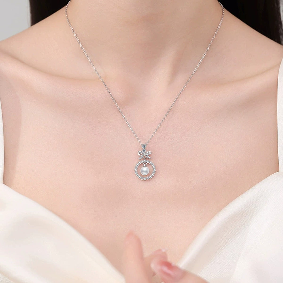 Bow Moissanite Freshwater Pearl Pendant Necklace with Cubic Zirconia in White Gold-Plated S925 Sterling Silver worn on neckline by model