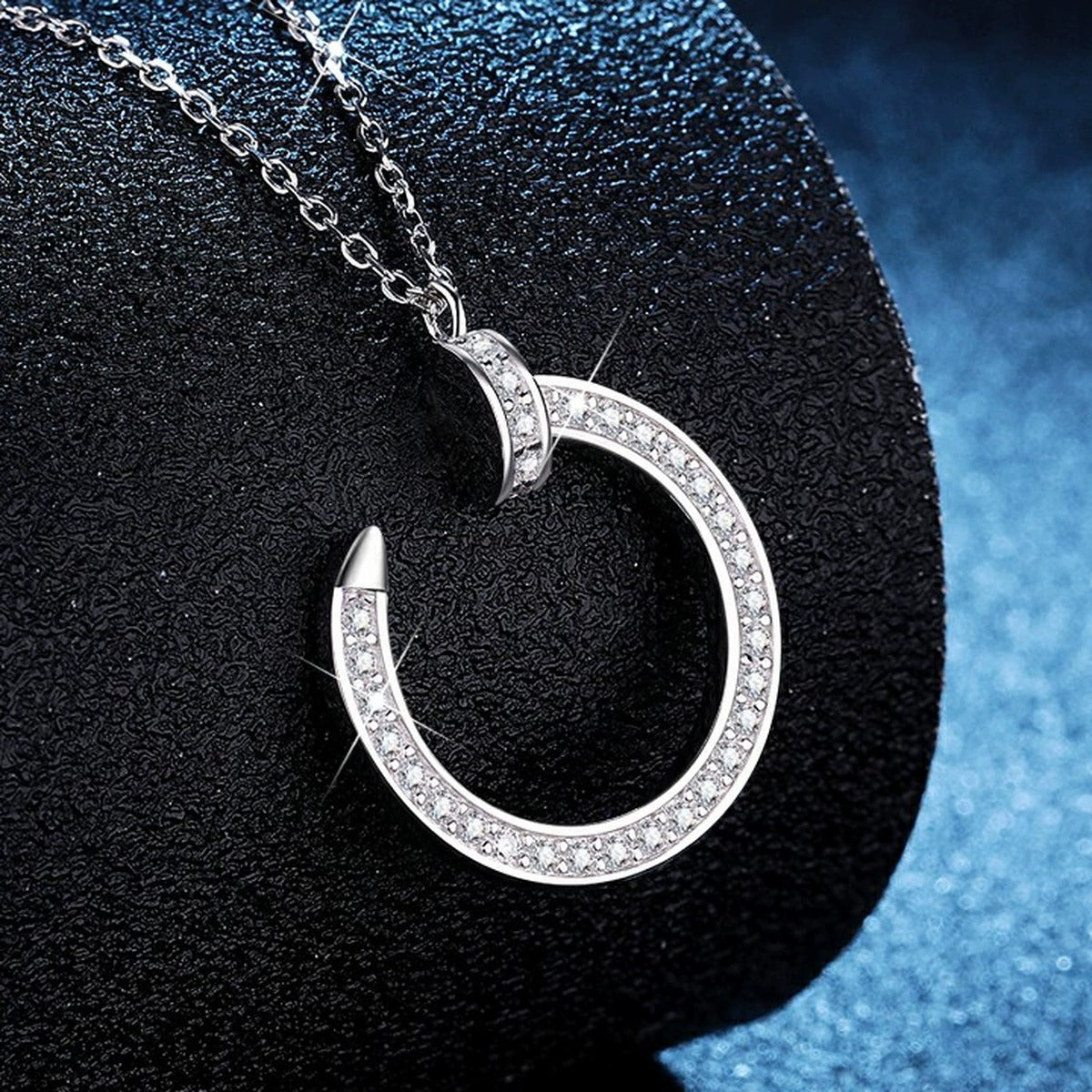 Crescent Moon Moissanite Pendant Necklace in Platinum-Plated S925 Sterling Silver blue background angled view